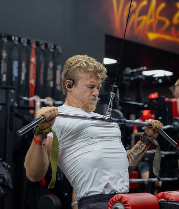 Athletic man performing a strength exercise in a dark gym with teal accents.